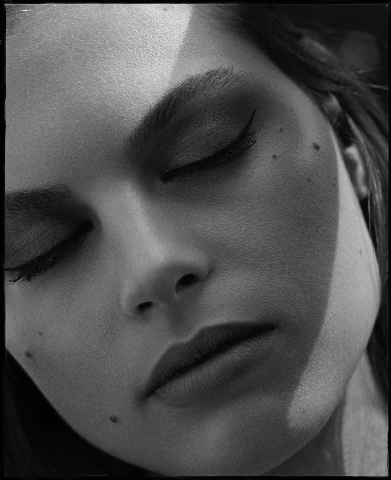 Close-up of a person's face with closed eyes, black and white photo
