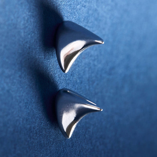 Pair of silver spike earrings on a blue background