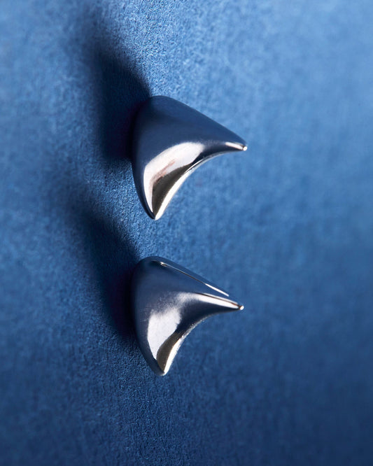 Pair of silver spike earrings on a blue background