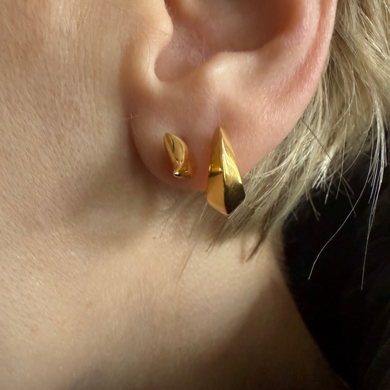 Close-up of a person wearing gold stud earrings.