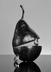 Metallic pear-shaped object with hanging rings on a reflective surface
