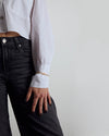 Person wearing a white shirt and black jeans against a plain background. Gold Vermeil bangle with a citrine lightning bolt.