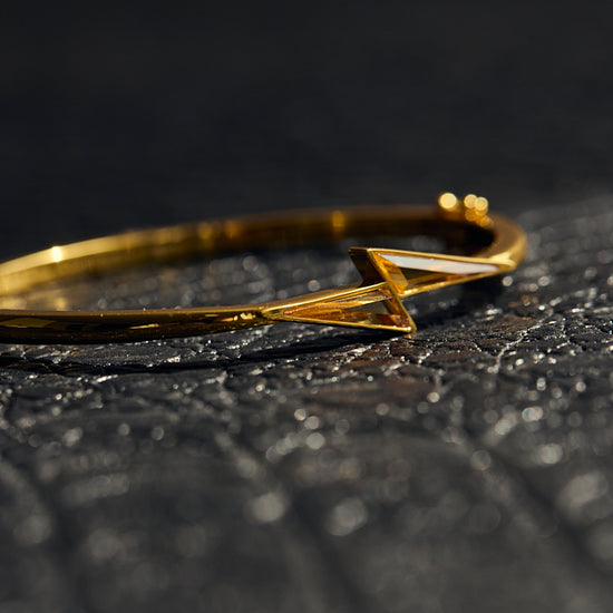Gold bracelet with a geometric design on a textured black surface