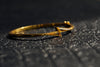 Gold bracelet with a geometric design on a textured black surface