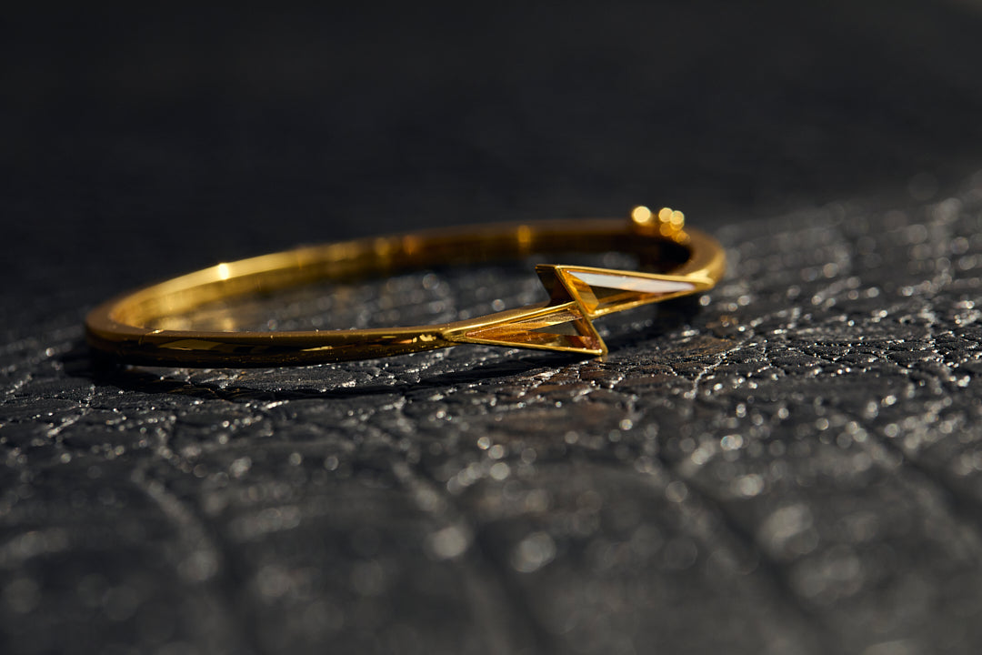 Gold bracelet with a geometric design on a textured black surface