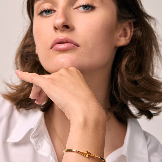Woman wearing a gold citrine thunder bracelet on a plain background