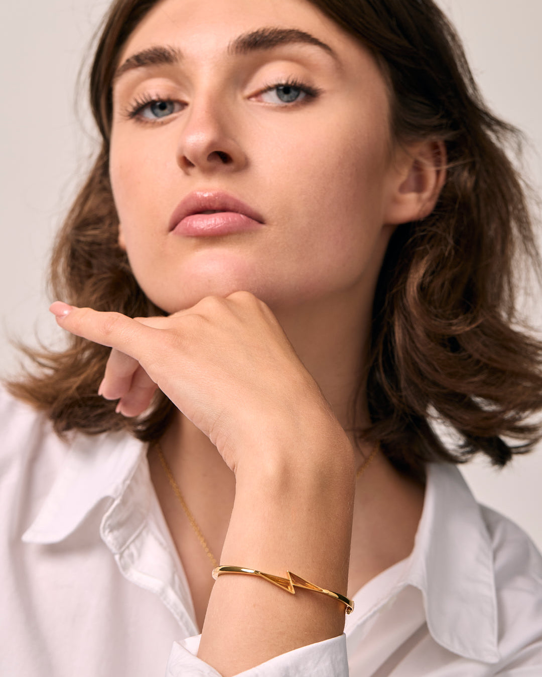 Woman wearing a gold citrine thunder bracelet on a plain background