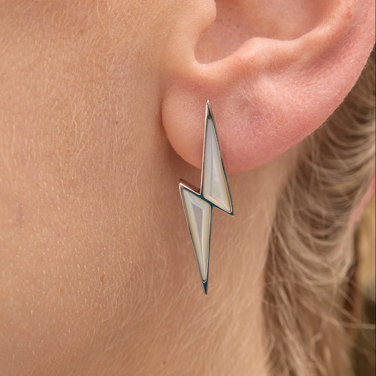 Close-up of an ear wearing a unique triangular thunderbolt earring.