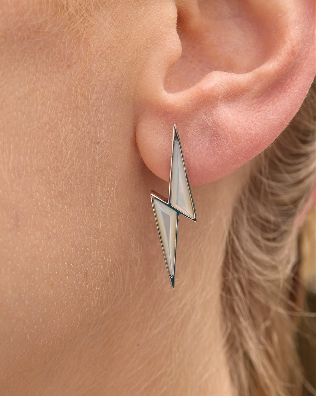 Close-up of an ear wearing a unique triangular thunderbolt earring.