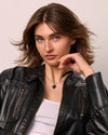 Woman wearing a black leather jacket and a black thorn shape onyx pendant/ against a neutral background