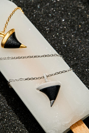 Two pendants on a white stand with a black background