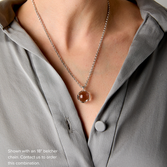 Necklace with a round pendant worn by a person in a gray shirt.