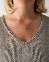 Close-up of a person wearing a gold necklace with a heart pendant.