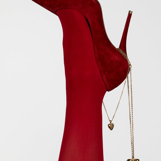 Red high-heeled shoes with gold heart-shaped accessories on a white background