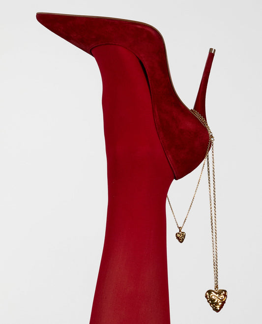 Red high-heeled shoes with gold heart-shaped accessories on a white background