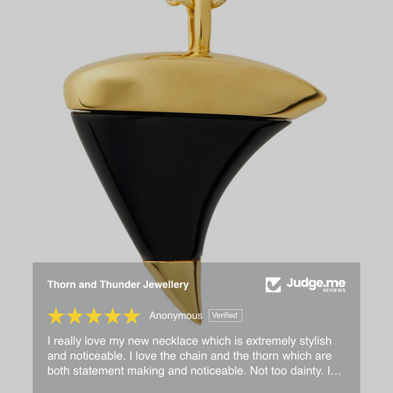Gold and black pendant necklace on a gray background with a 5-star rating from Judge.me.