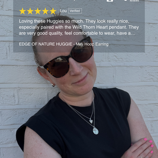 Woman wearing sunglasses and a black top with a white brick wall background