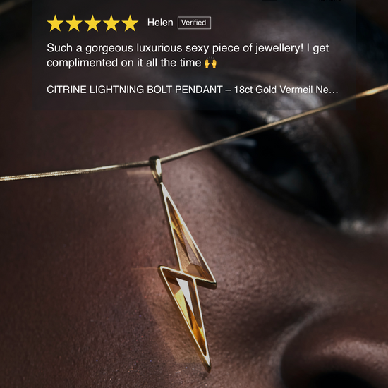 Gold lightning bolt pendant on a dark background with a jewelry brand and rating visible.