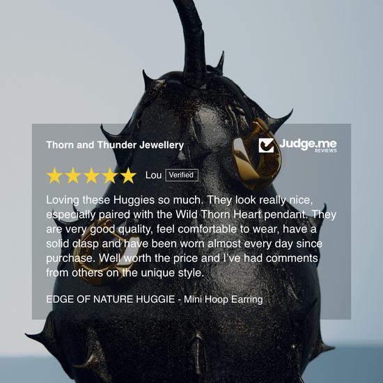 Black nature-themed earring with a reflective surface on a gray background, featuring a 5-star rating from 'Judge.me'.