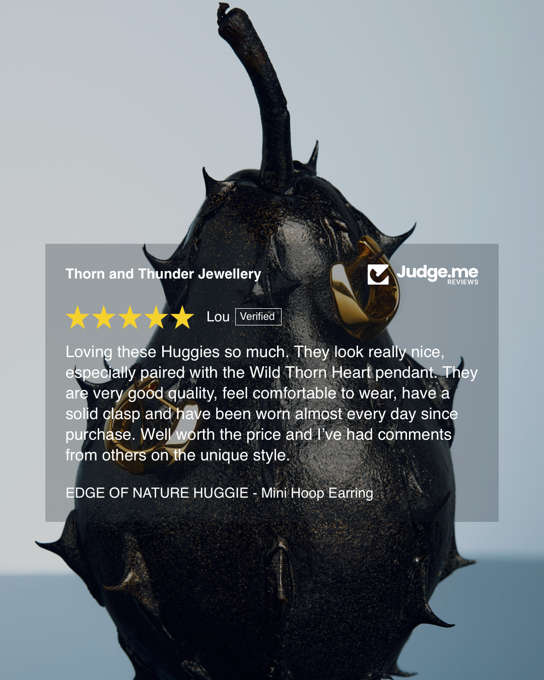 Black nature-themed earring with a reflective surface on a gray background, featuring a 5-star rating from 'Judge.me'.