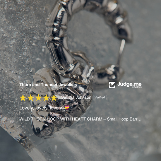 Silver hoop earring with heart charm on a textured surface, surrounded by product reviews.
